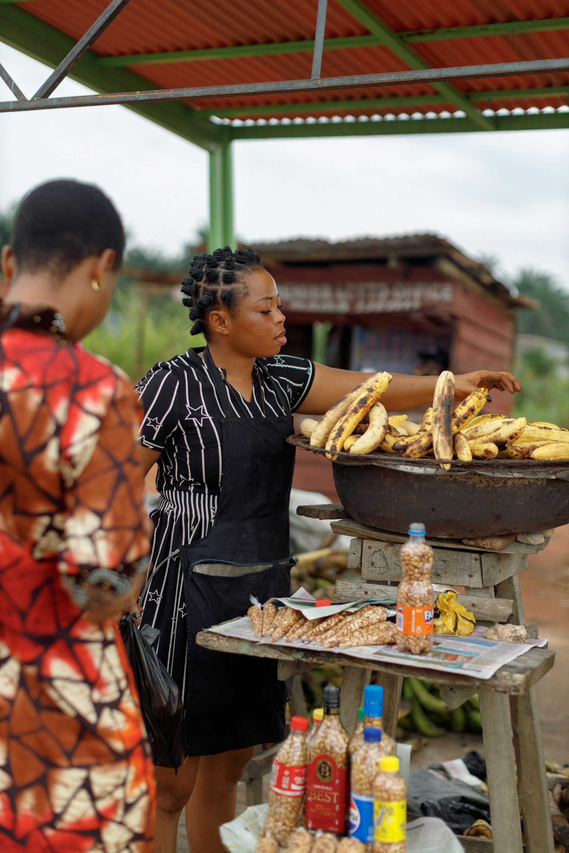 A woman selects grilled plantains at a roadside food stand in Cameroon