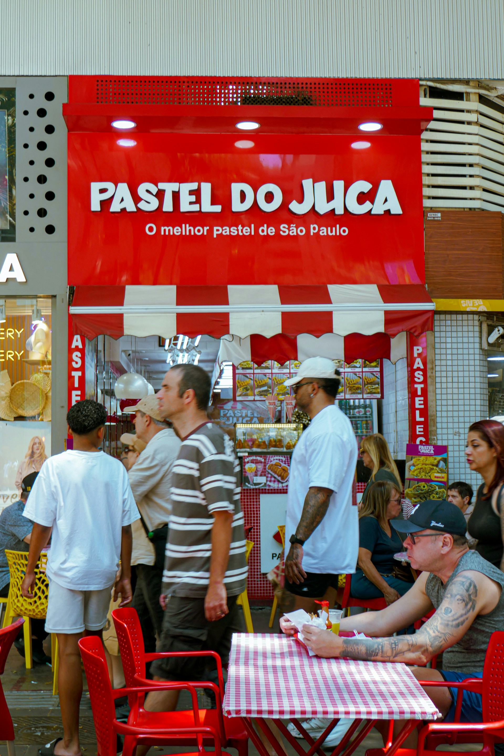 Crowds gather at a vibrant red-and-white street food stall in Sao Paulo, Brazil