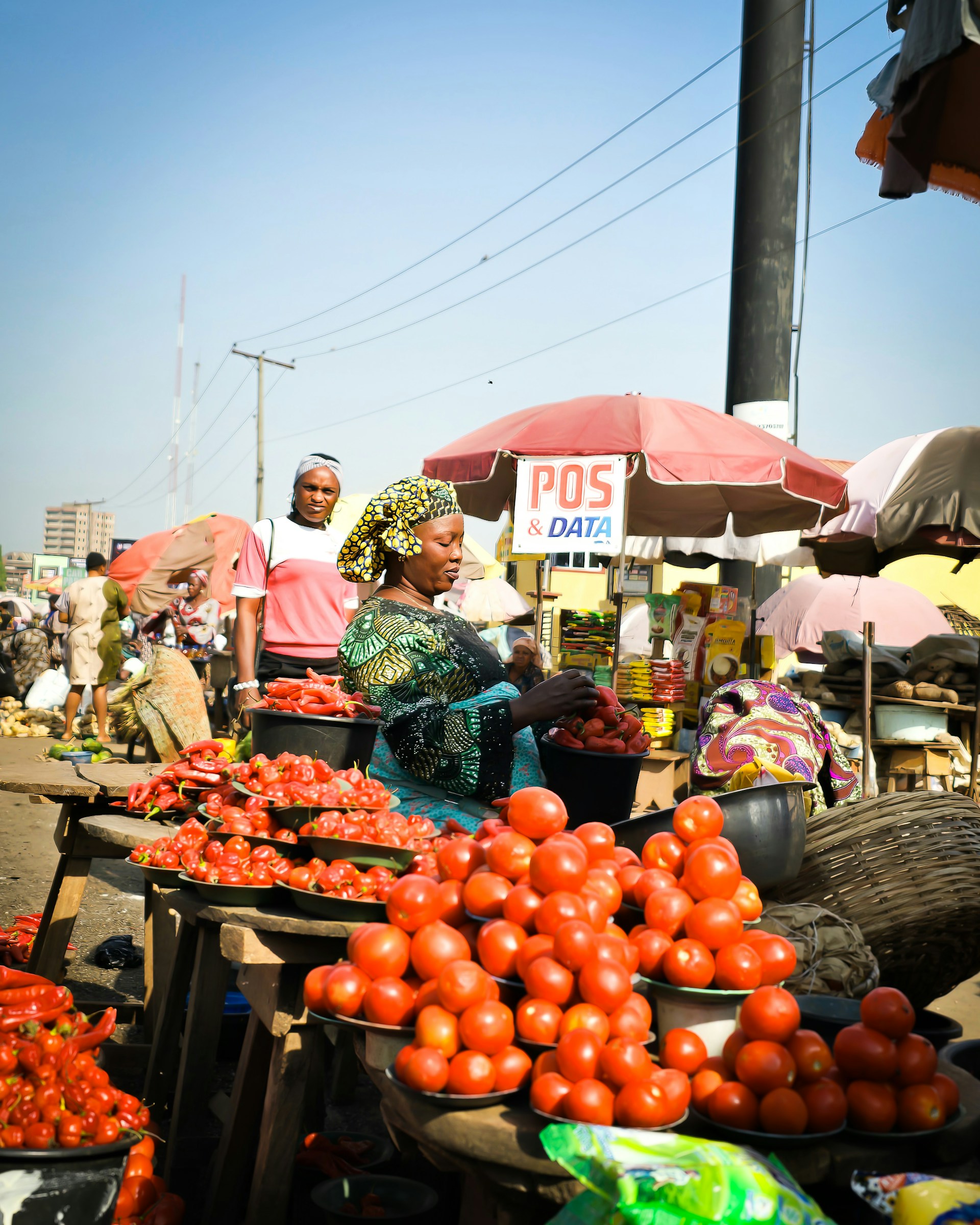 A vendor arranges fresh tomatoes and peppers at an open-air market in Lagos, Nigeria